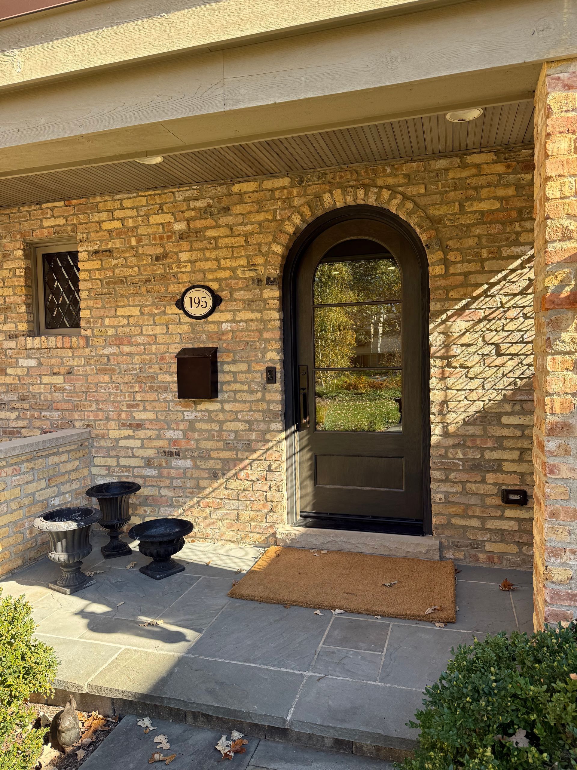 A brick house with a black door and a porch.