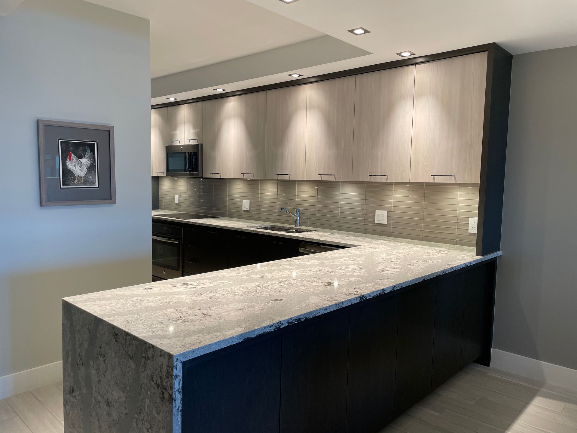 A kitchen with a large island and a picture of a chicken on the wall.