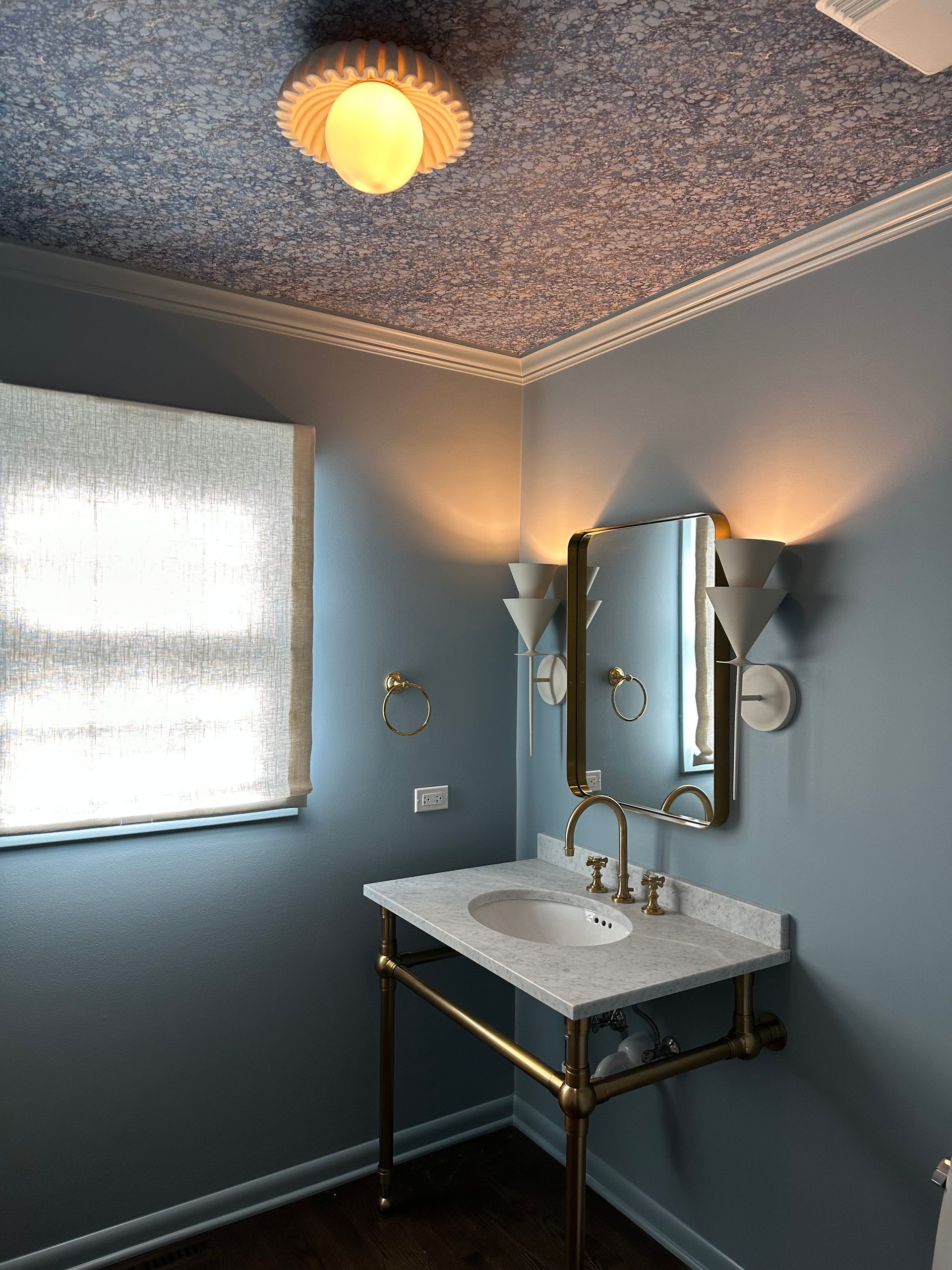 A bathroom with a sink , mirror and window.