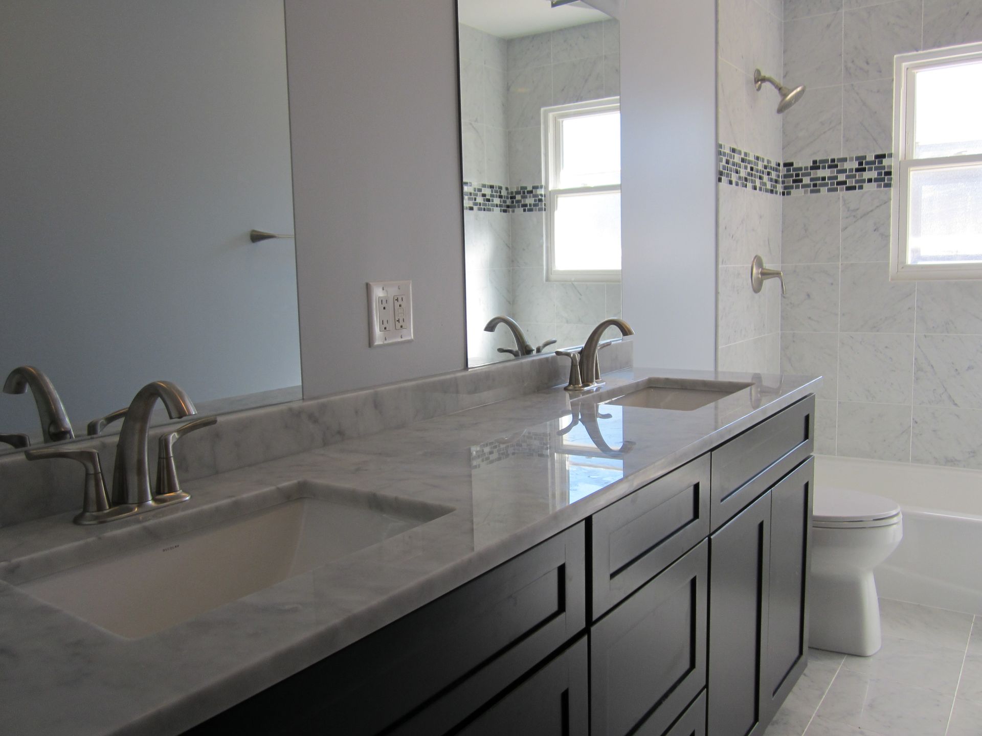 A bathroom with two sinks , a toilet , and a shower.