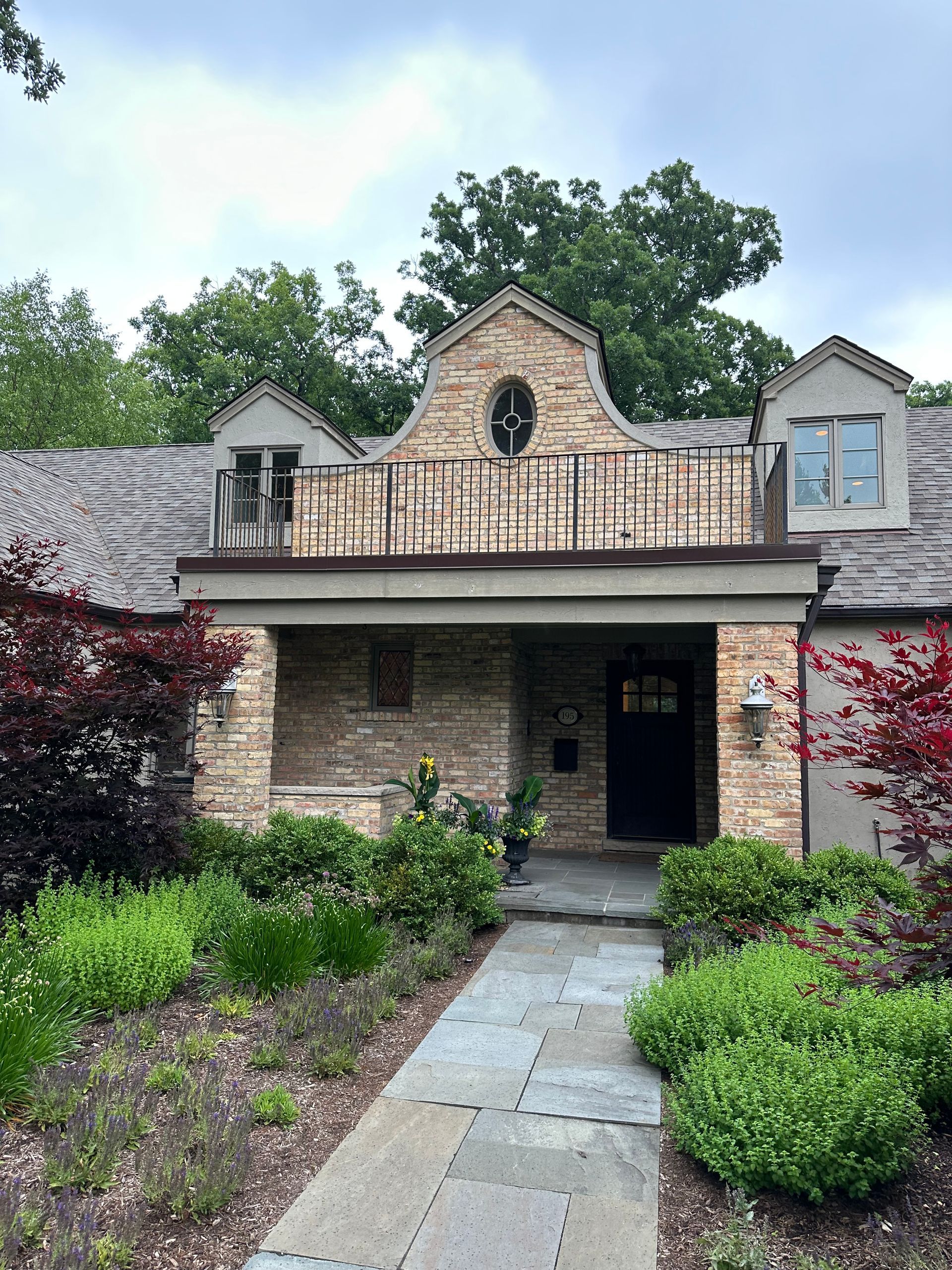 A large brick house with a balcony and a walkway leading to it.