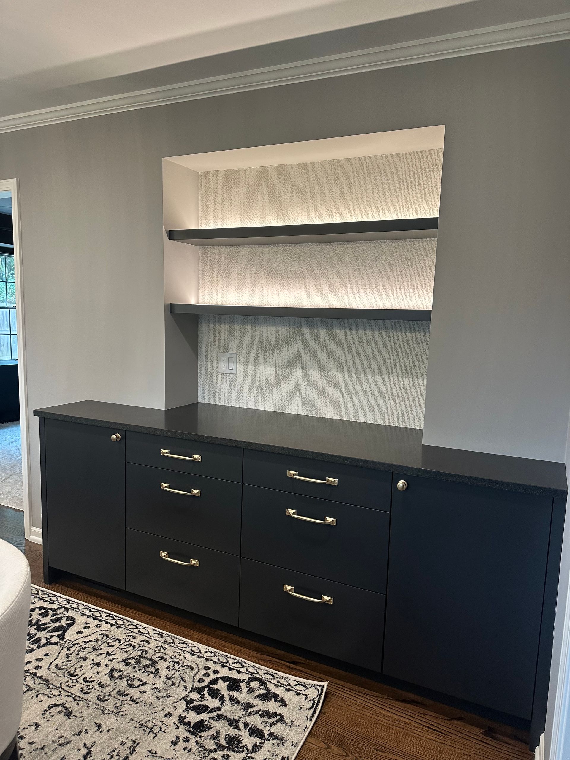 A living room with black cabinets , drawers , and a rug.