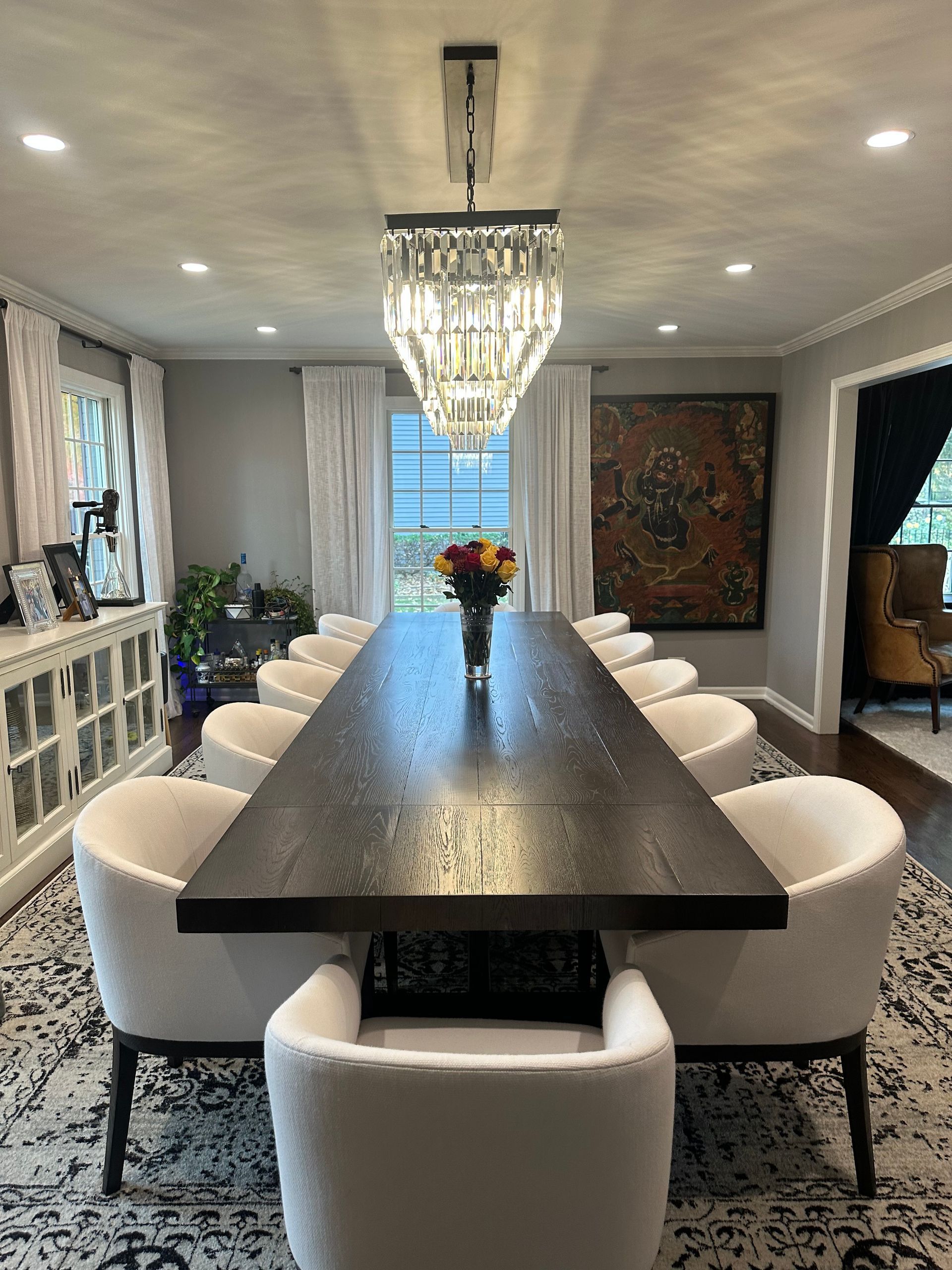A dining room with a long table and chairs and a chandelier.
