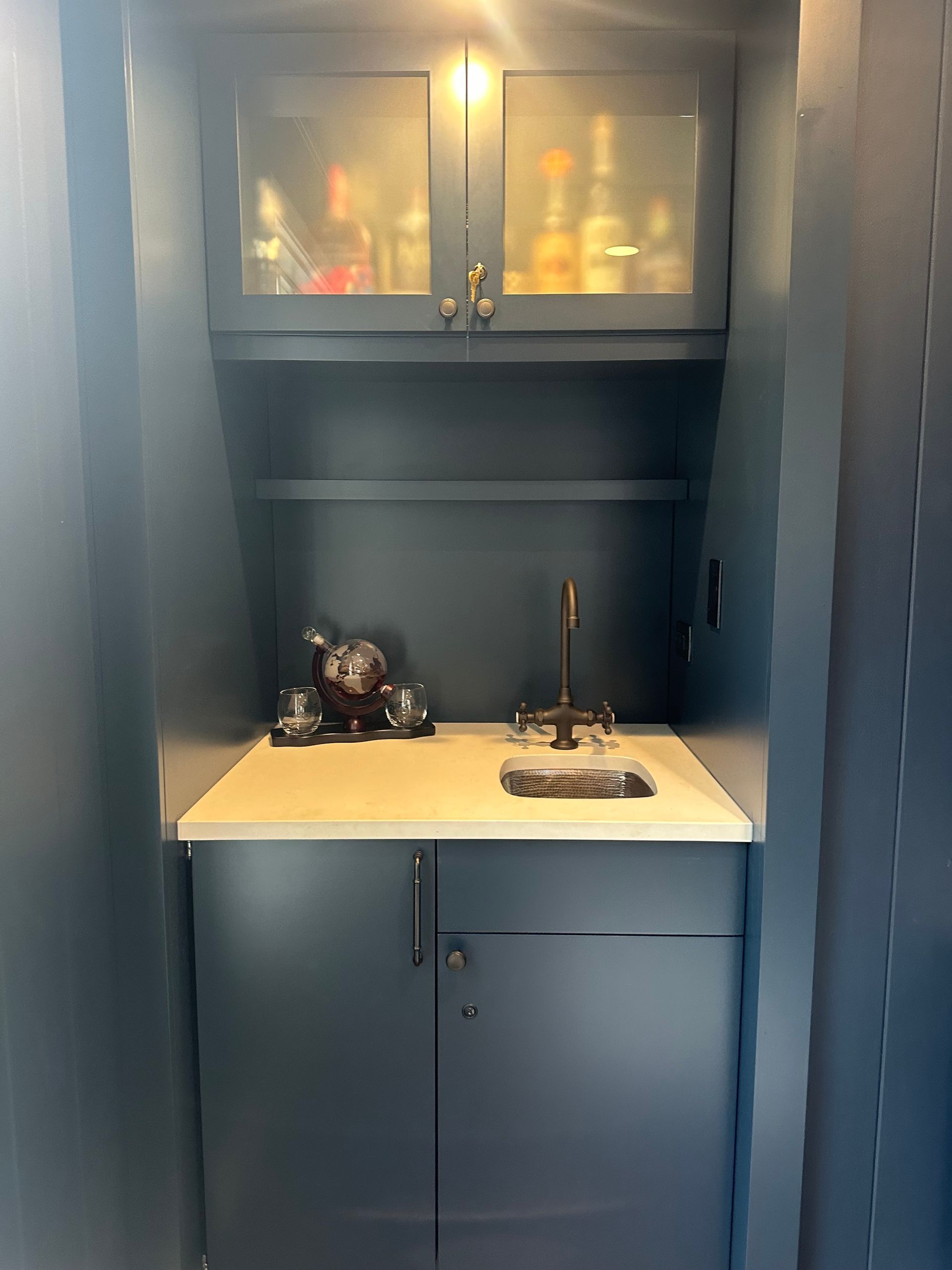 A small kitchen with a sink , cabinets and shelves.