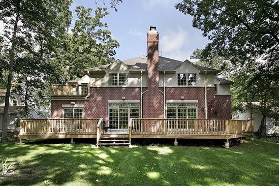 The back of a large brick house with a large wooden deck.
