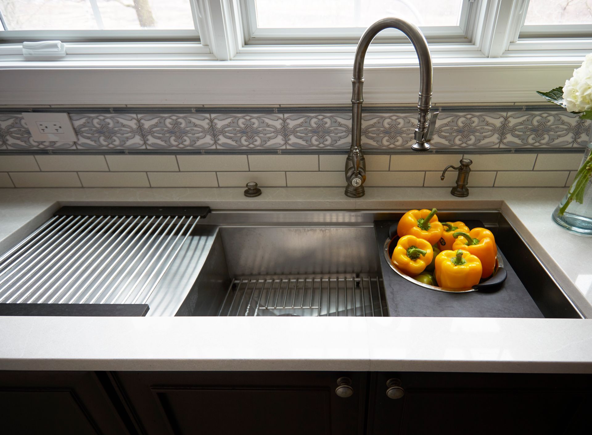 A kitchen sink with a tray of peppers in it