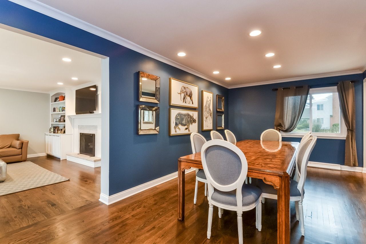 A dining room with a wooden table and chairs and blue walls.
