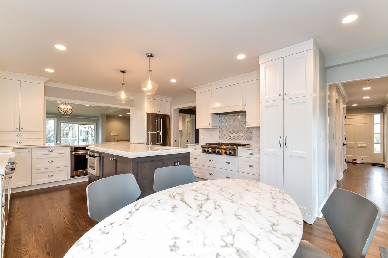 There is a marble table in the middle of the kitchen.