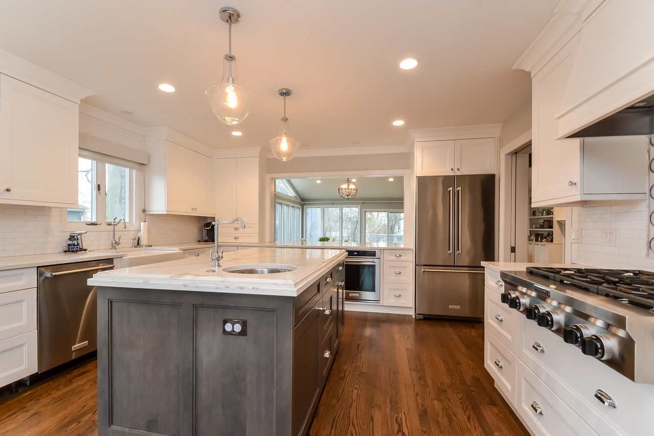 A kitchen with white cabinets and stainless steel appliances and a large island in the middle.