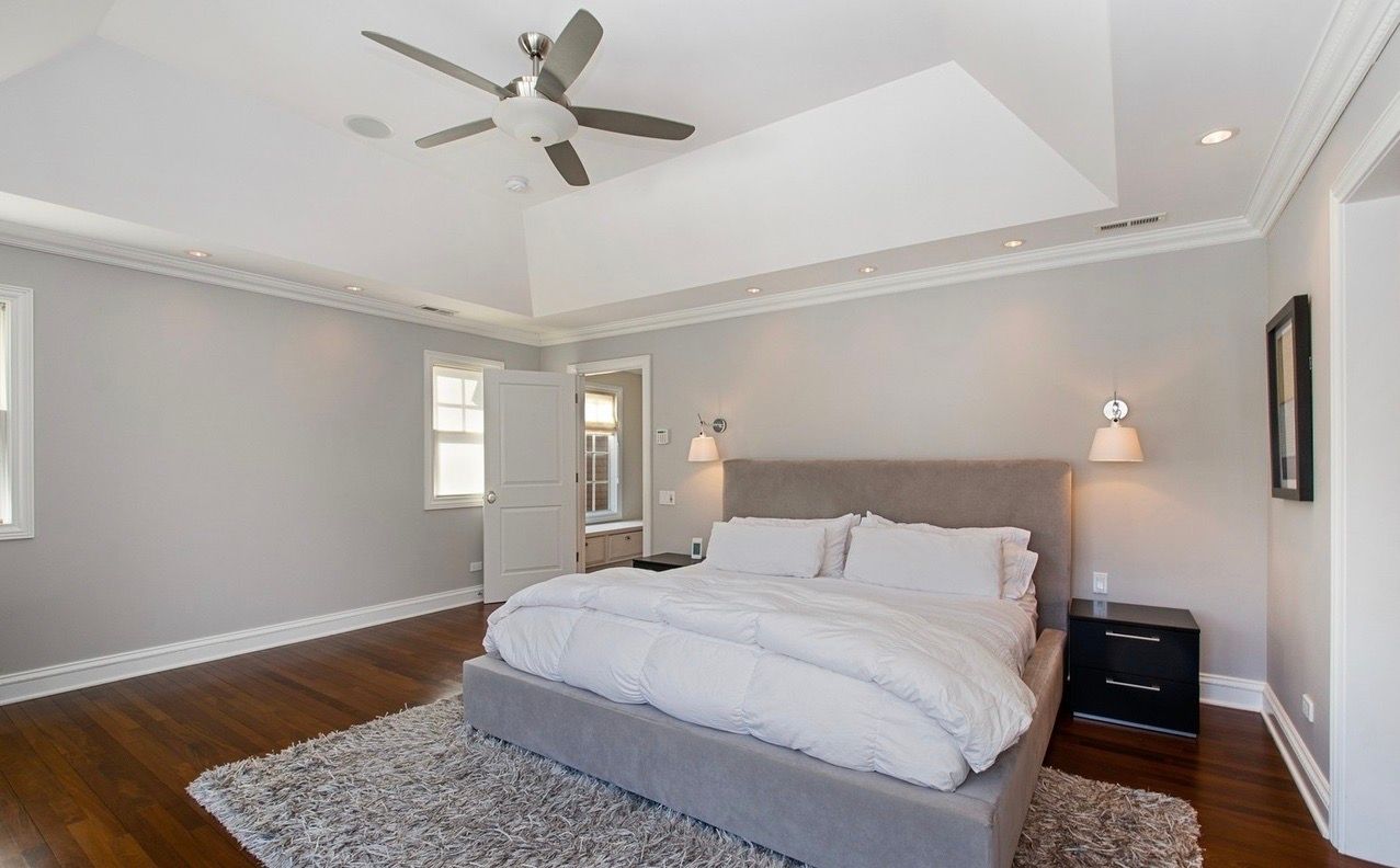 A bedroom with a large bed and a ceiling fan