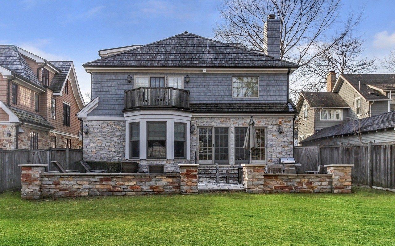 The back of a large house with a large lawn in front of it.
