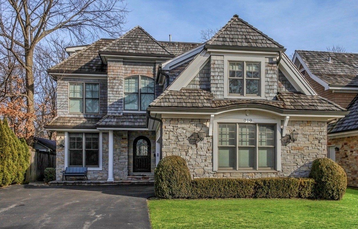 A large brick house with a shingle roof is sitting on top of a lush green lawn.