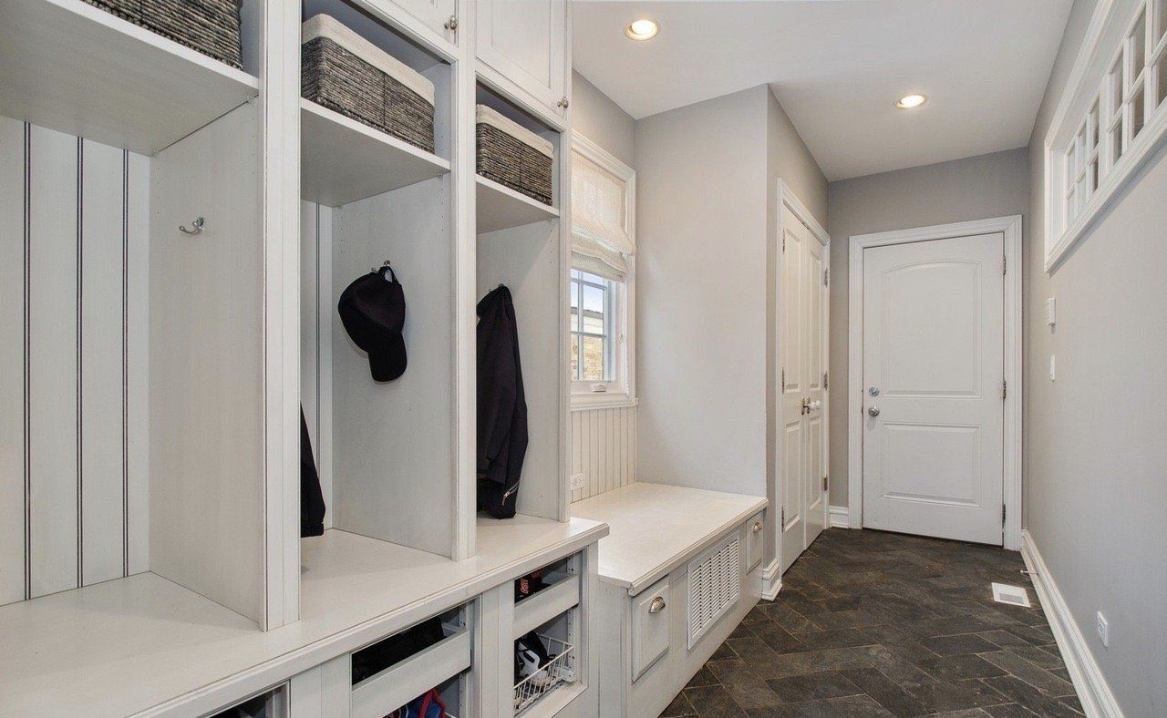 A hallway with a bench and shelves in a house.