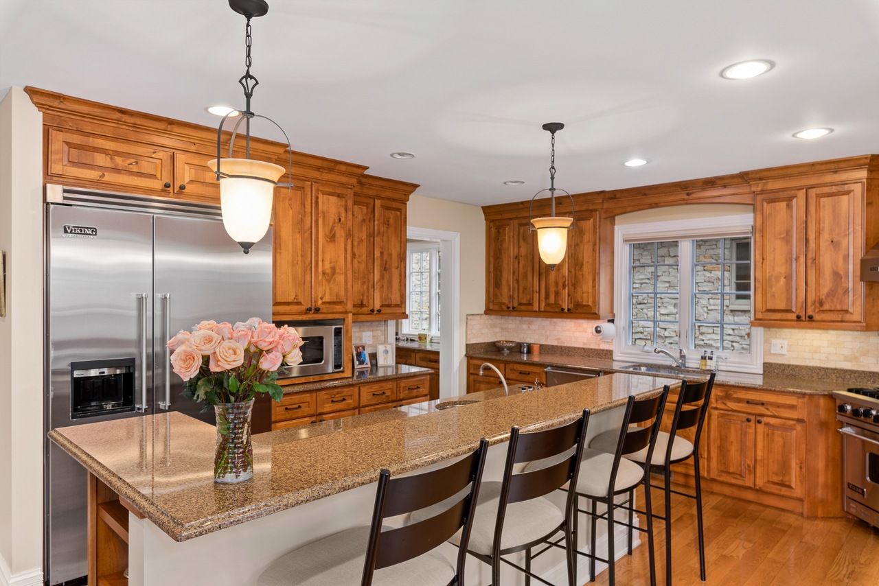 A kitchen with wooden cabinets , granite counter tops , stainless steel appliances and a large island.