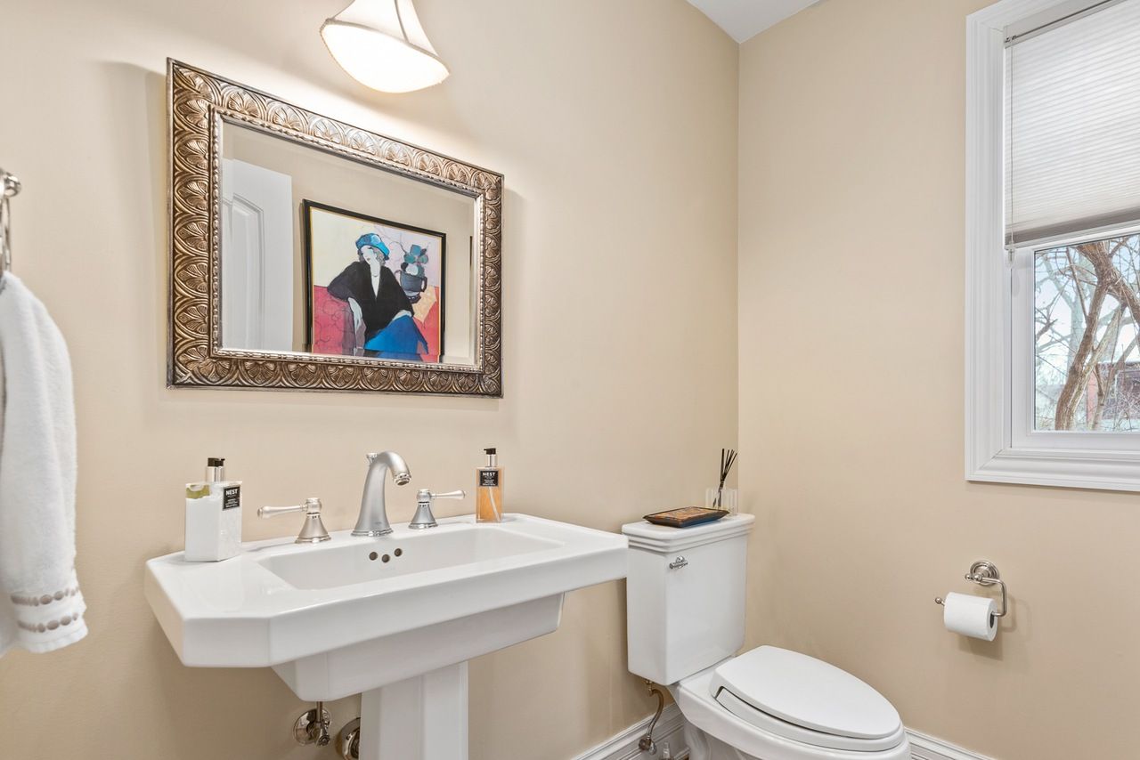 A bathroom with a sink , toilet , mirror and window.