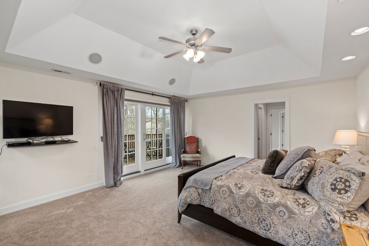 A bedroom with a bed , television and ceiling fan.
