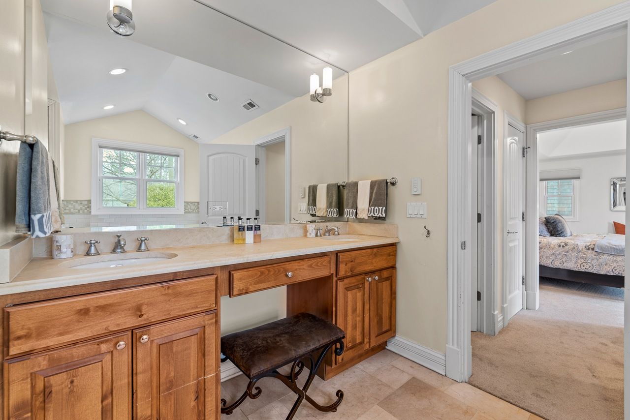 A bathroom with a vanity , sink , mirror and bench.