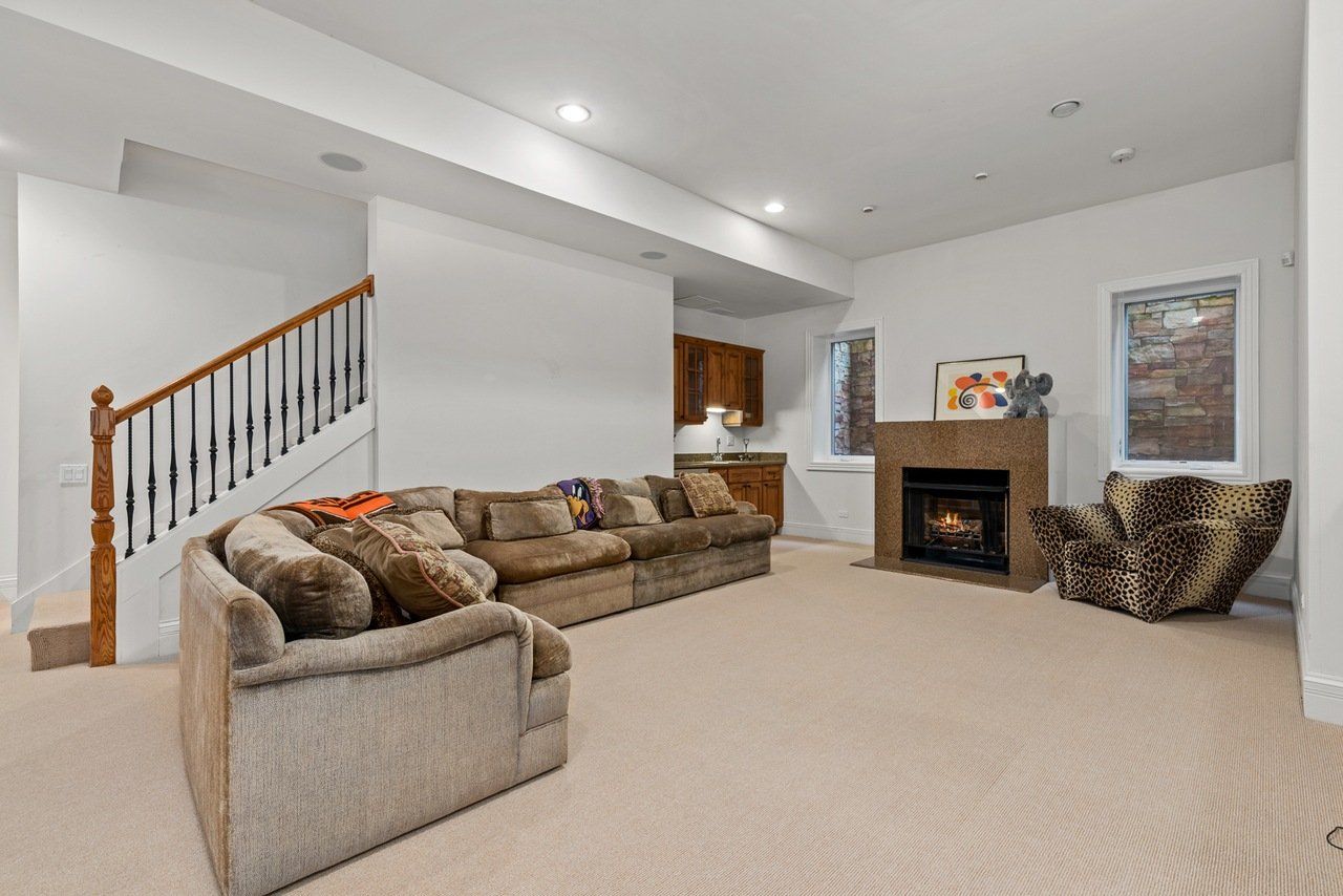 A living room with a couch , chair , fireplace and stairs.