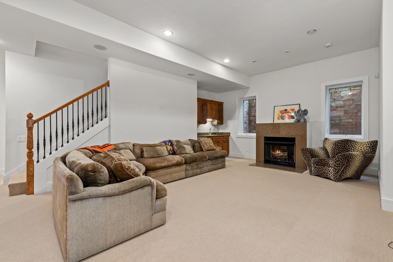 A living room with a couch , chair , fireplace and stairs.