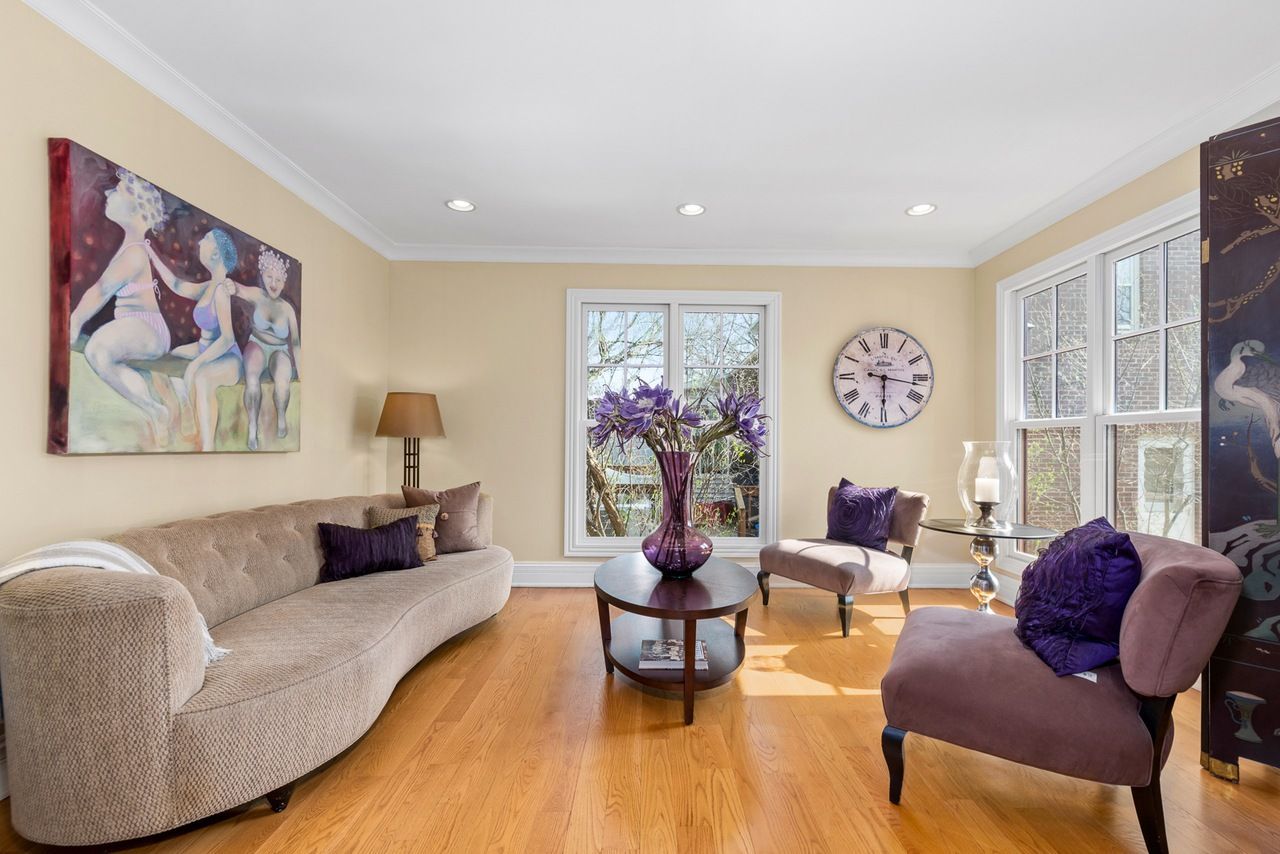 A living room with a couch and chairs and a clock on the wall