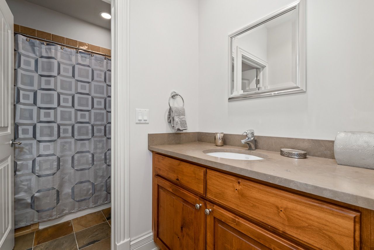 A bathroom with a sink , mirror and shower curtain.