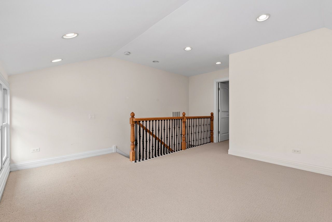 An empty room with a wooden railing and stairs in a house.