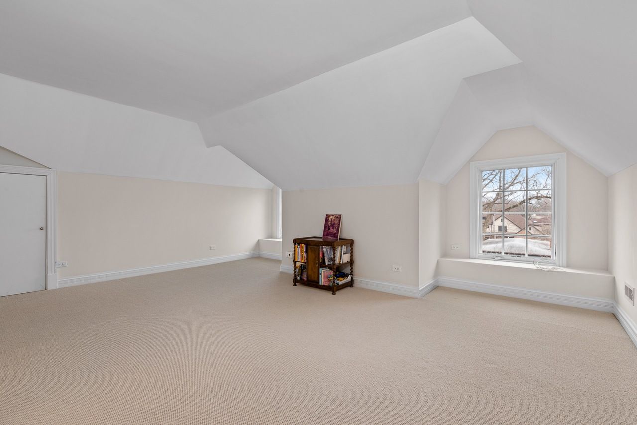 An empty attic with a window and a bookshelf.