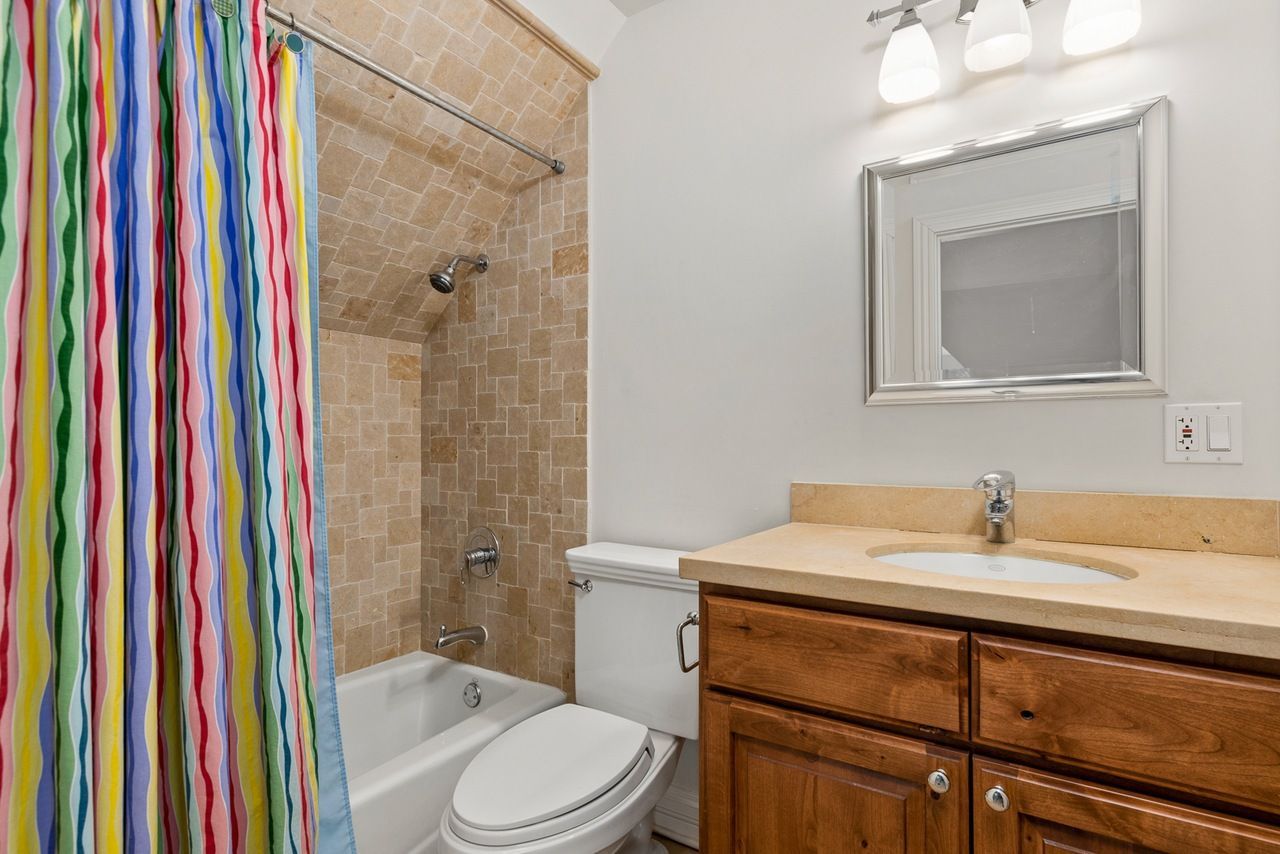 A bathroom with a toilet , sink , bathtub and shower curtain.
