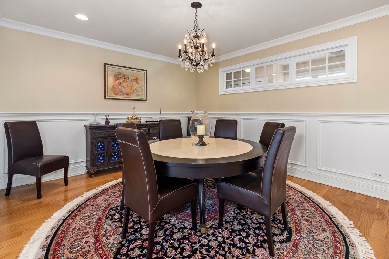 A dining room with a round table and chairs and a chandelier.