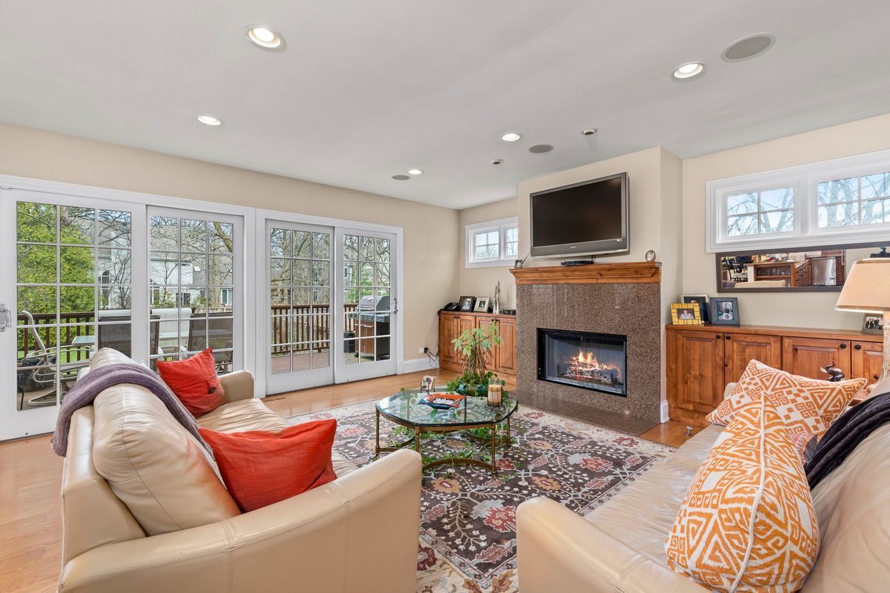 A living room with a couch , chair , fireplace and television.