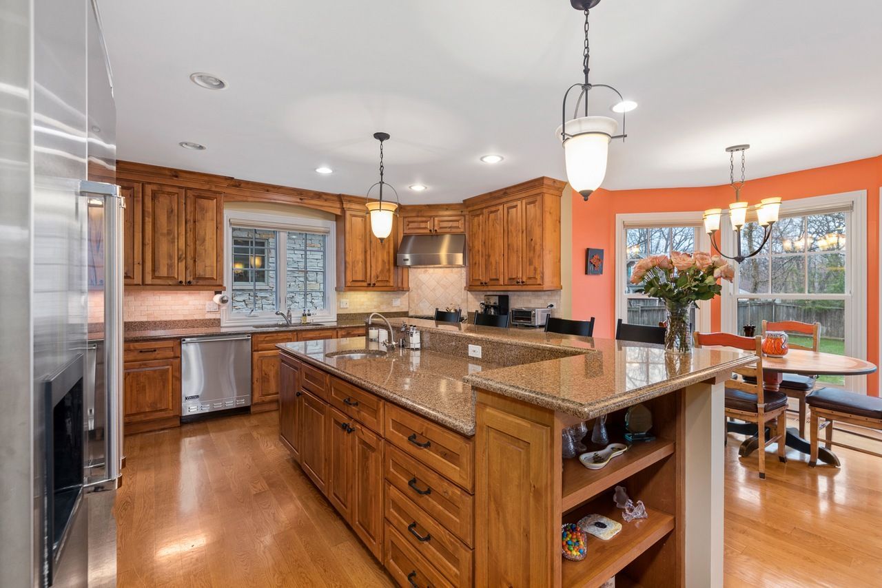 A kitchen with wooden cabinets , granite counter tops , stainless steel appliances and a large island.