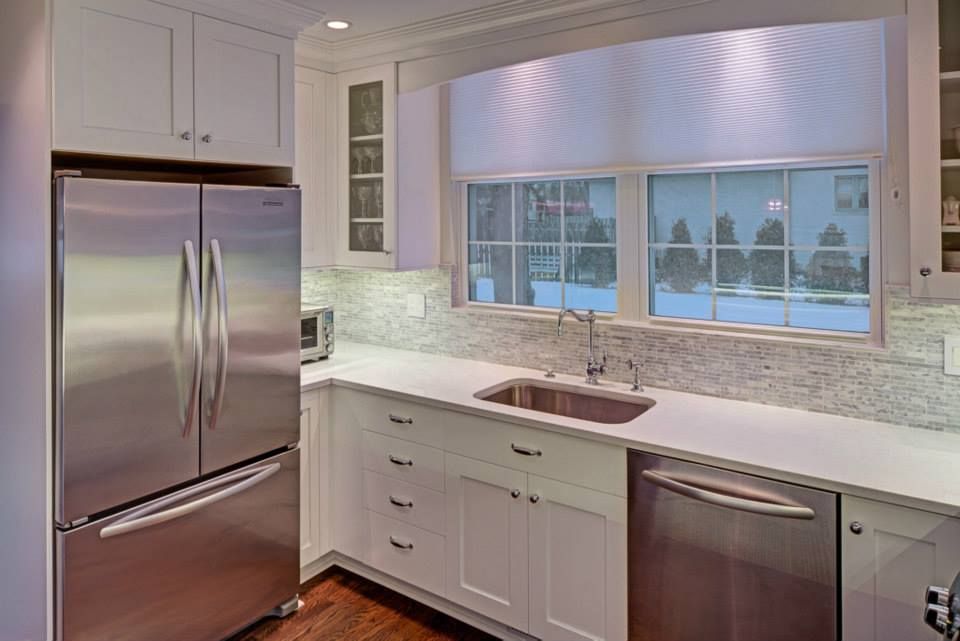A kitchen with stainless steel appliances , white cabinets , a sink and a refrigerator.