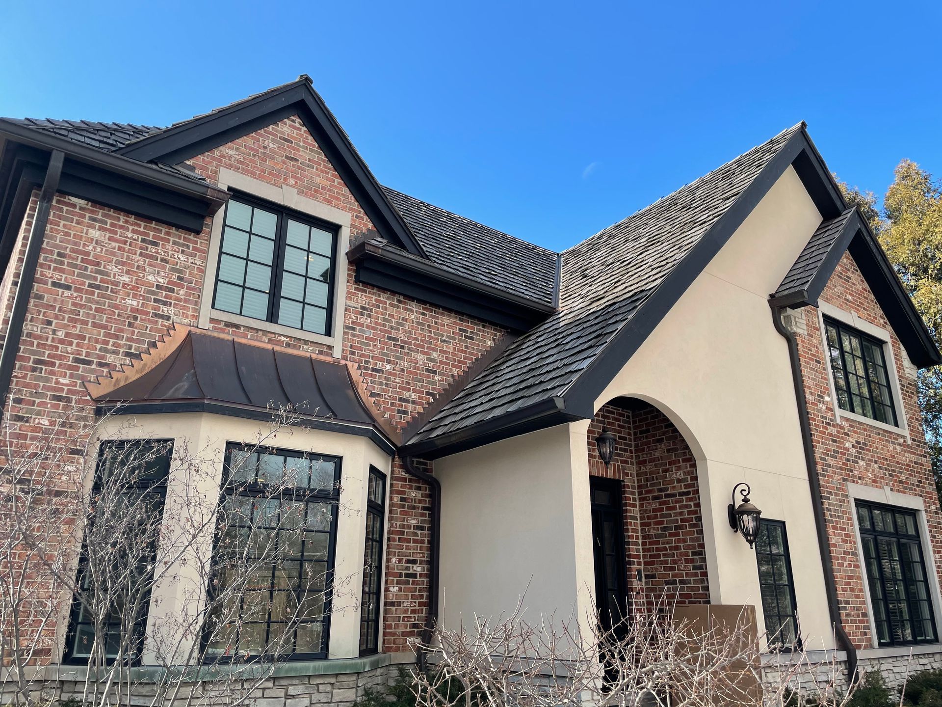 A large brick house with a black roof and a lot of windows.