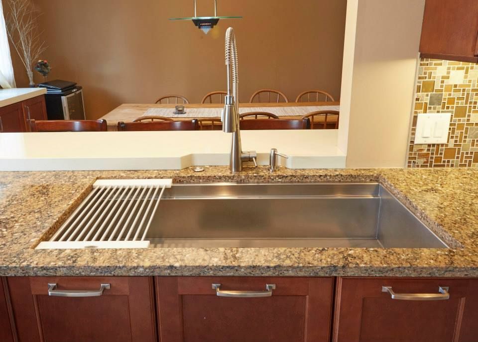 A kitchen with a stainless steel sink and granite counter tops