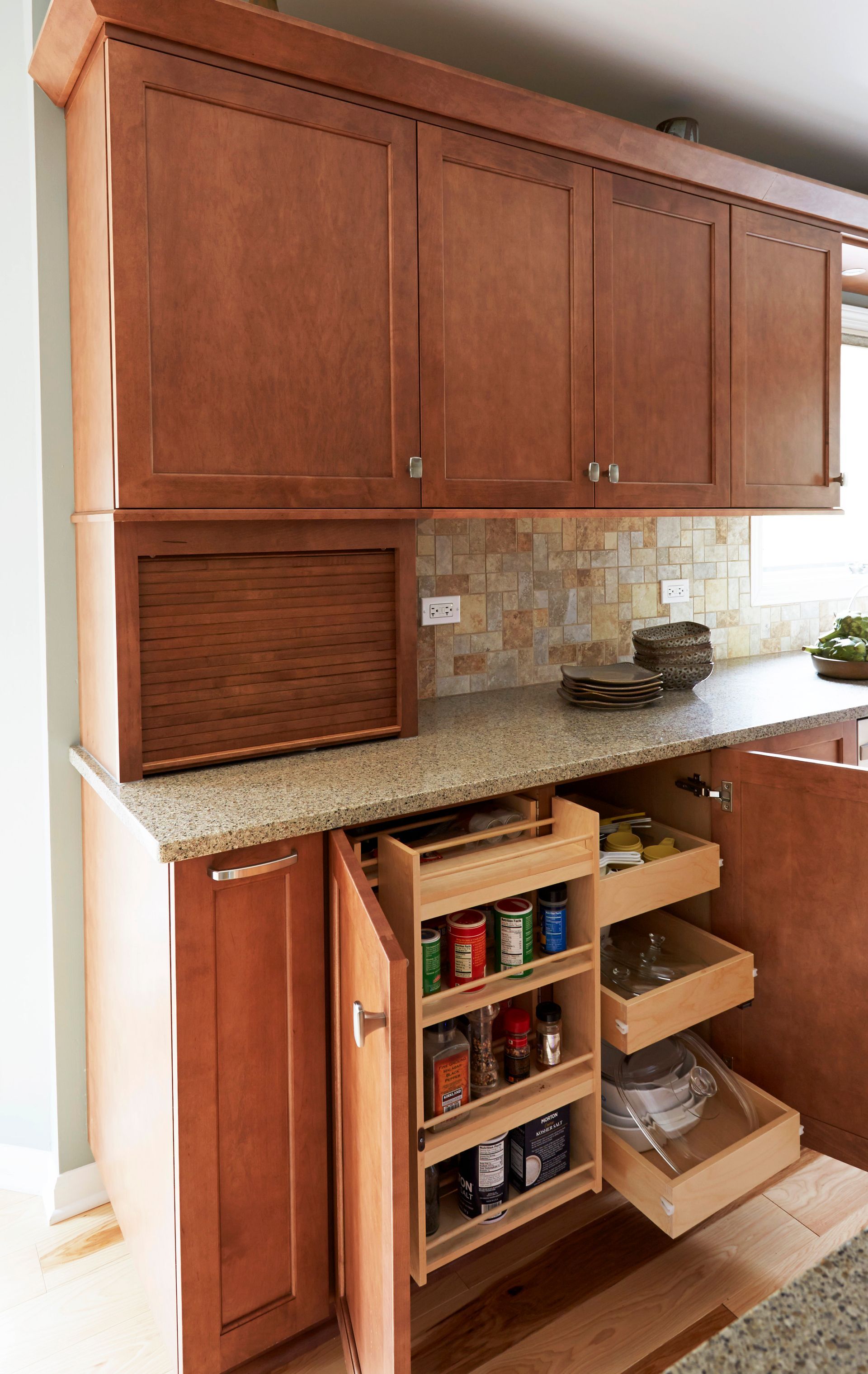 A kitchen with wooden cabinets and a pull out spice rack