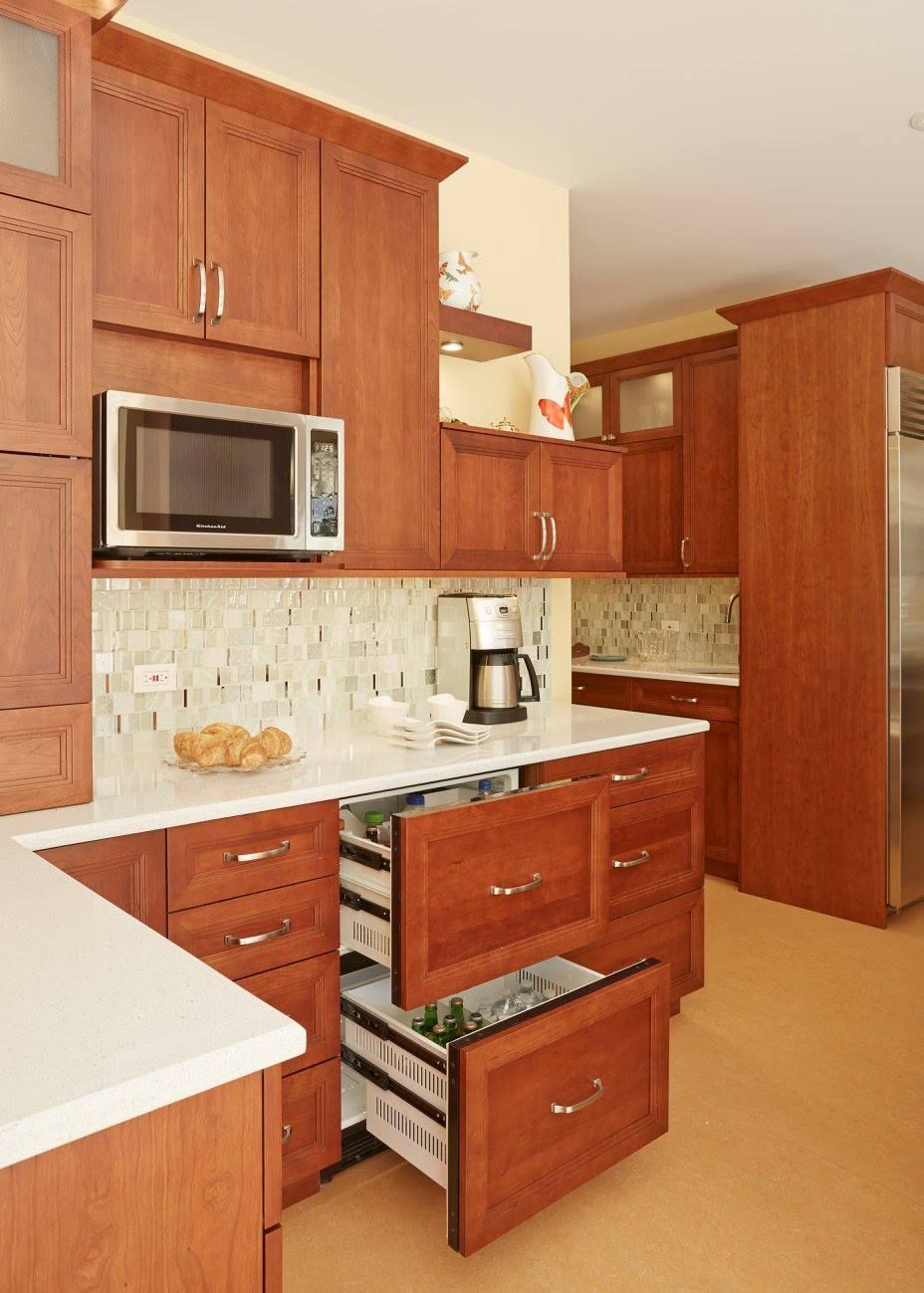 A kitchen with wooden cabinets and drawers and a microwave