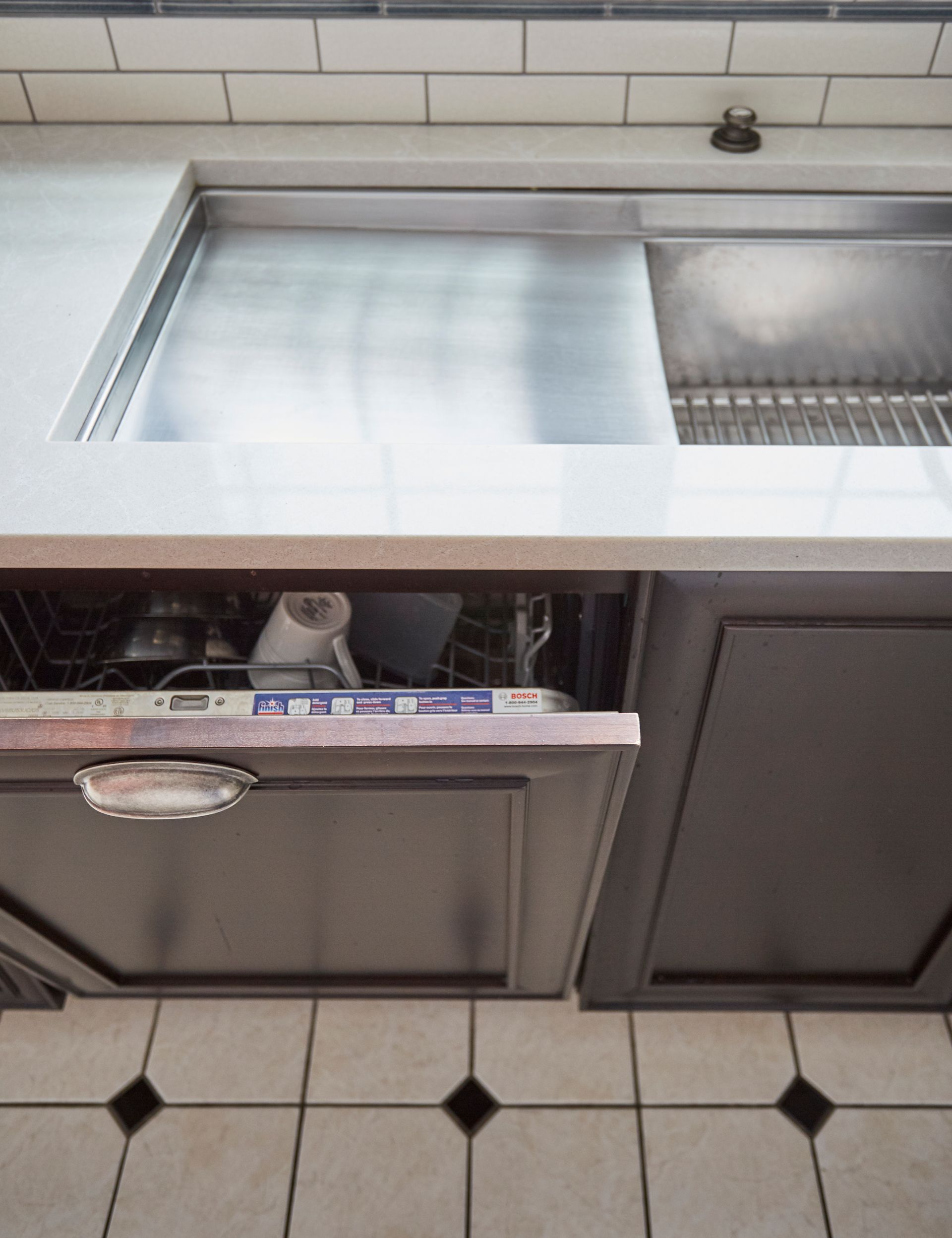 A kitchen with a sink and a dishwasher with the door open
