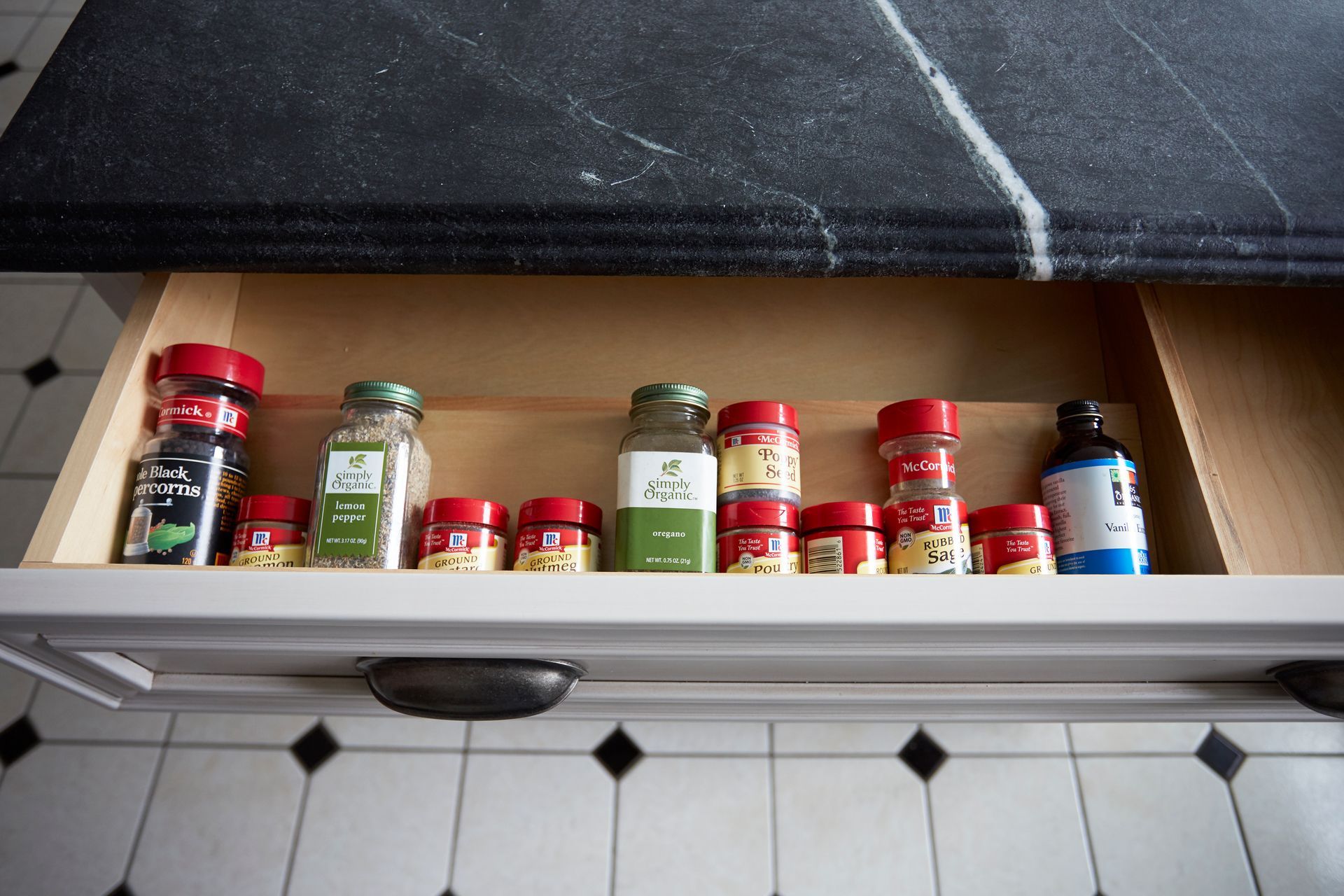 A kitchen drawer filled with bottles and jars of spices.