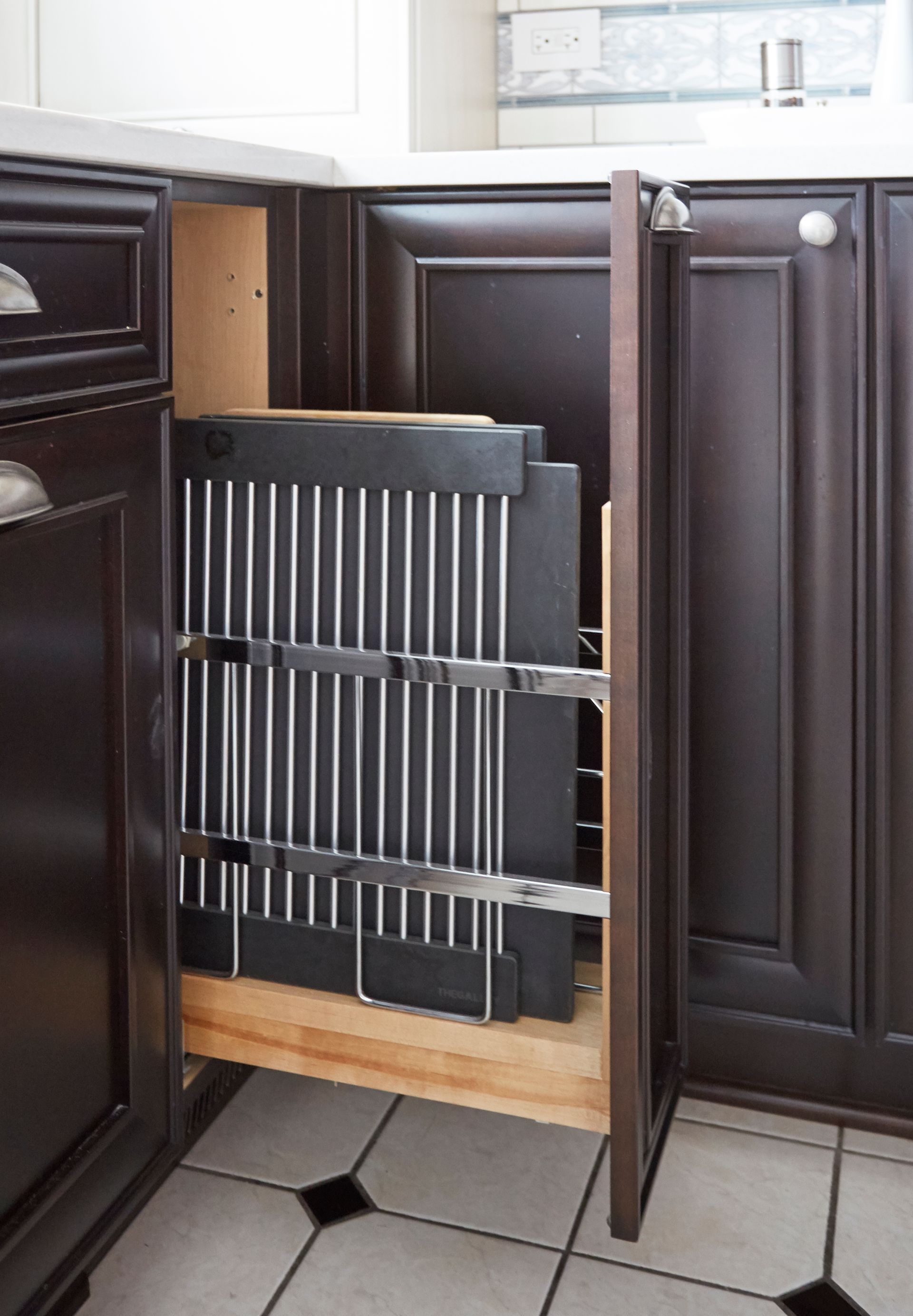 A kitchen cabinet with a pull out drawer for cutting boards and knives