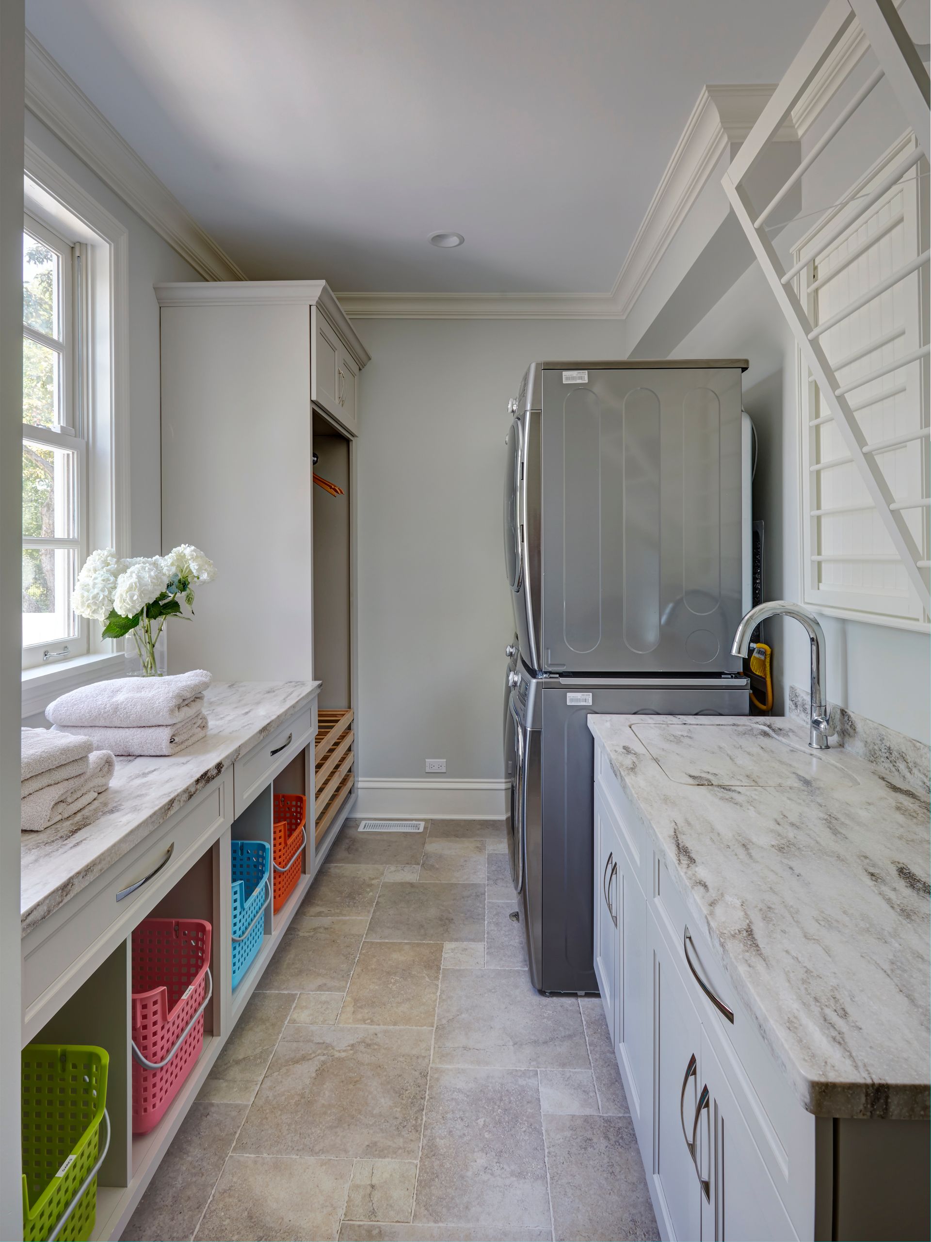 A laundry room with white cabinets and a stainless steel refrigerator