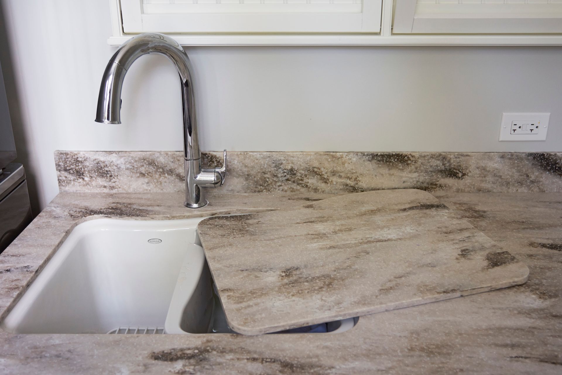 A kitchen sink with a faucet on top of a granite counter top.