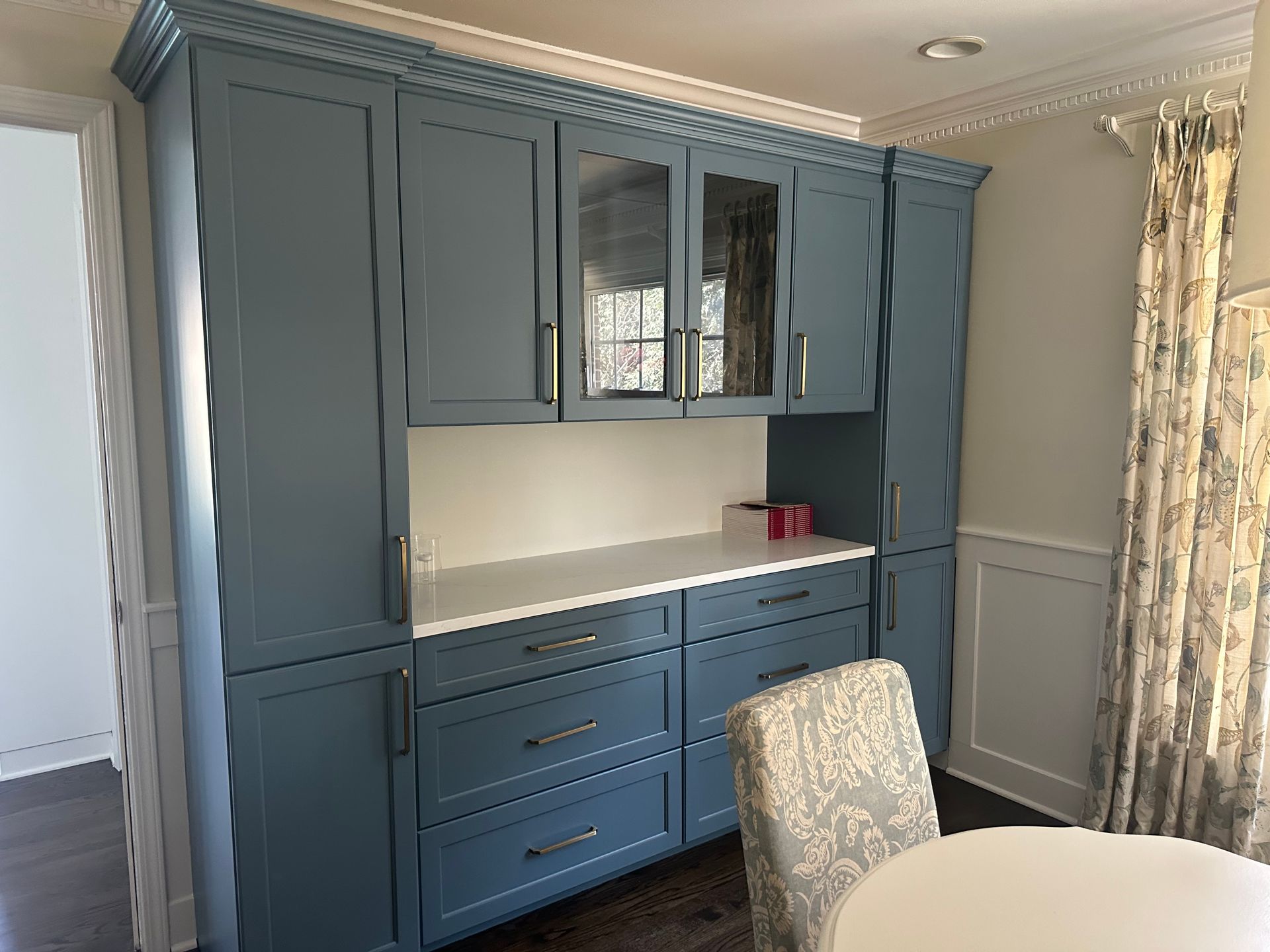 A kitchen with blue cabinets and a white table and chairs.
