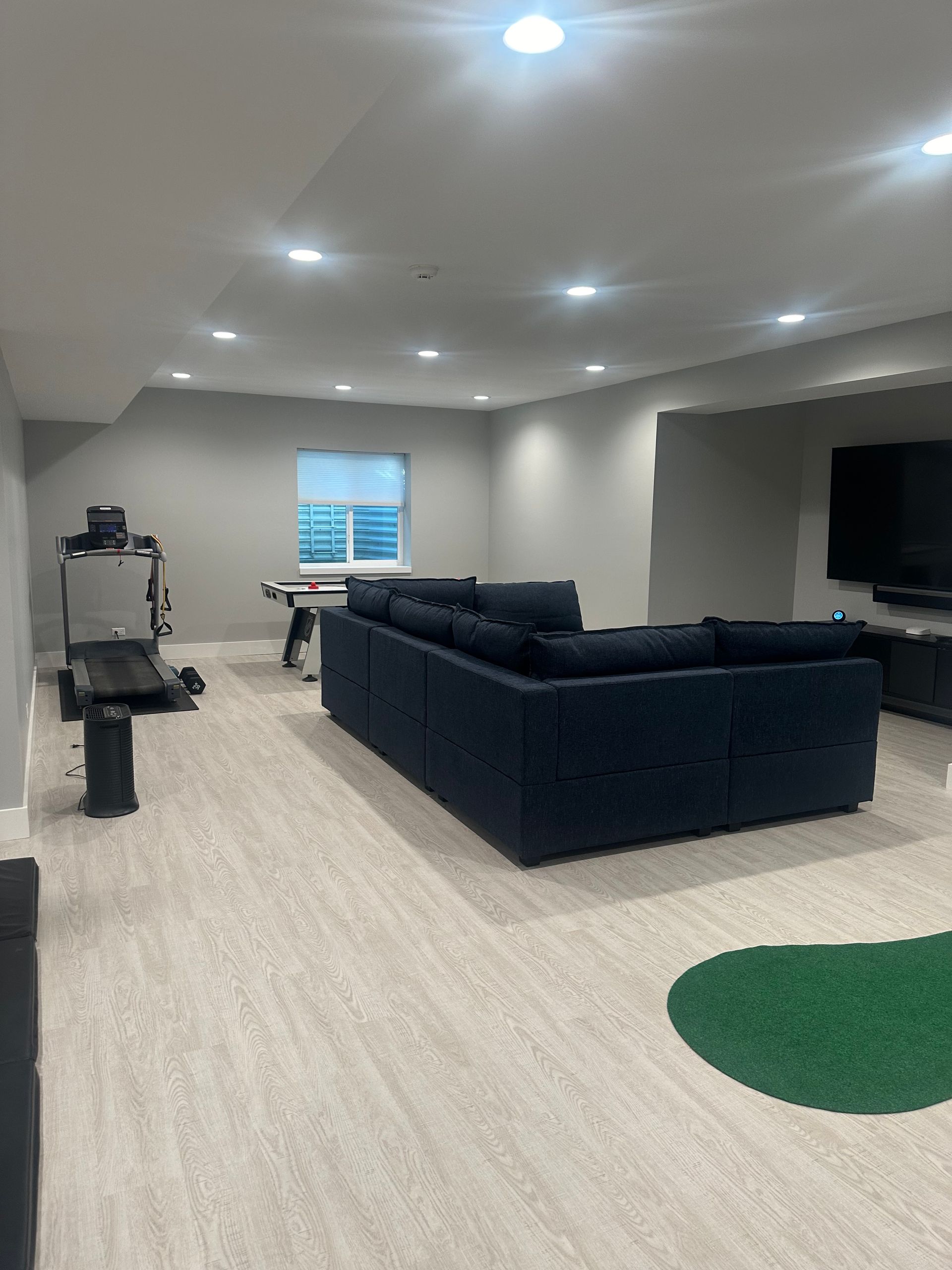 A living room with a couch , treadmill , and television.