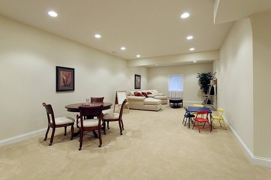 A basement with a table , chairs , and a couch.