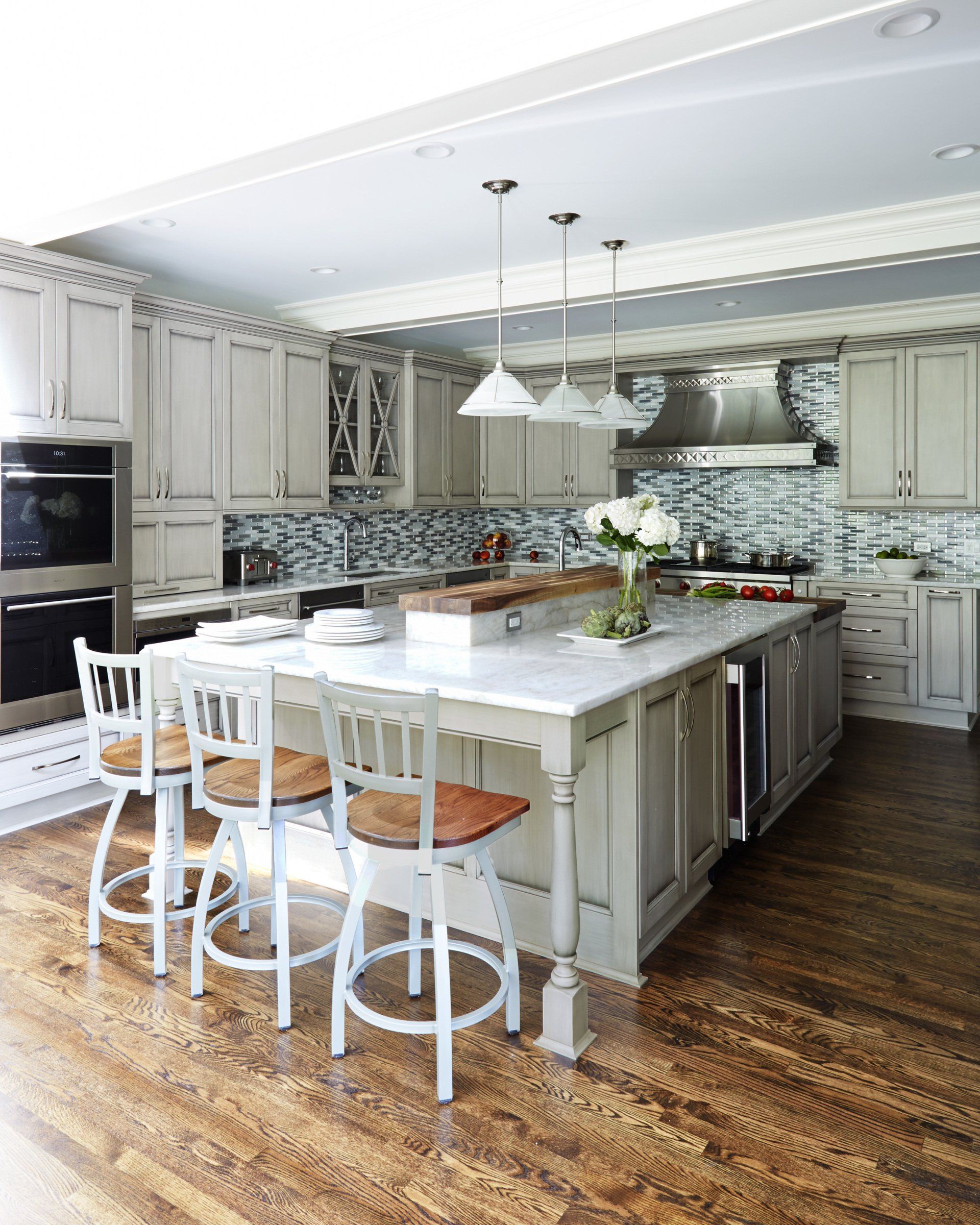 A kitchen with white cabinets and stools and a large island