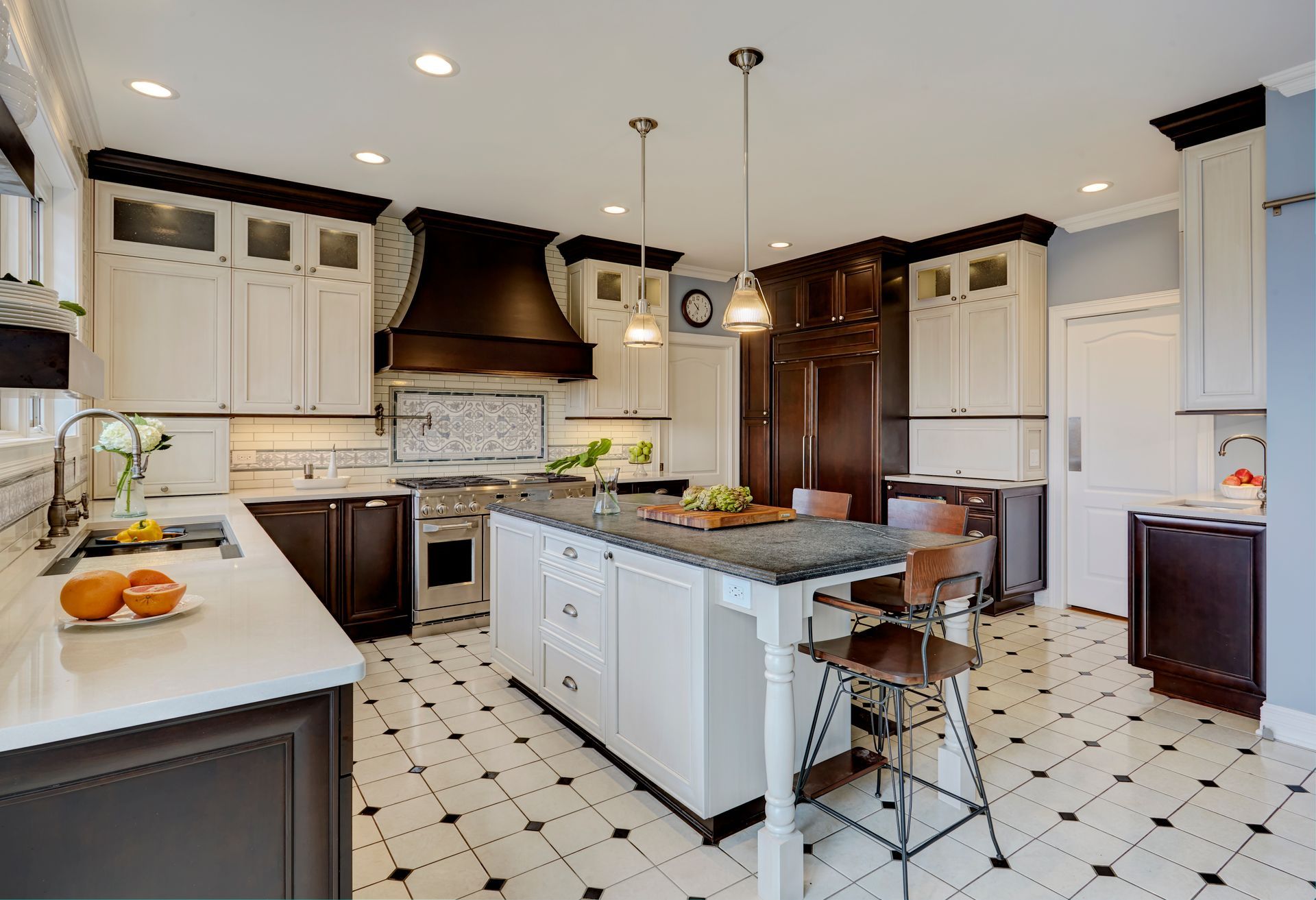 A kitchen with a large island in the middle and black and white tile floors.