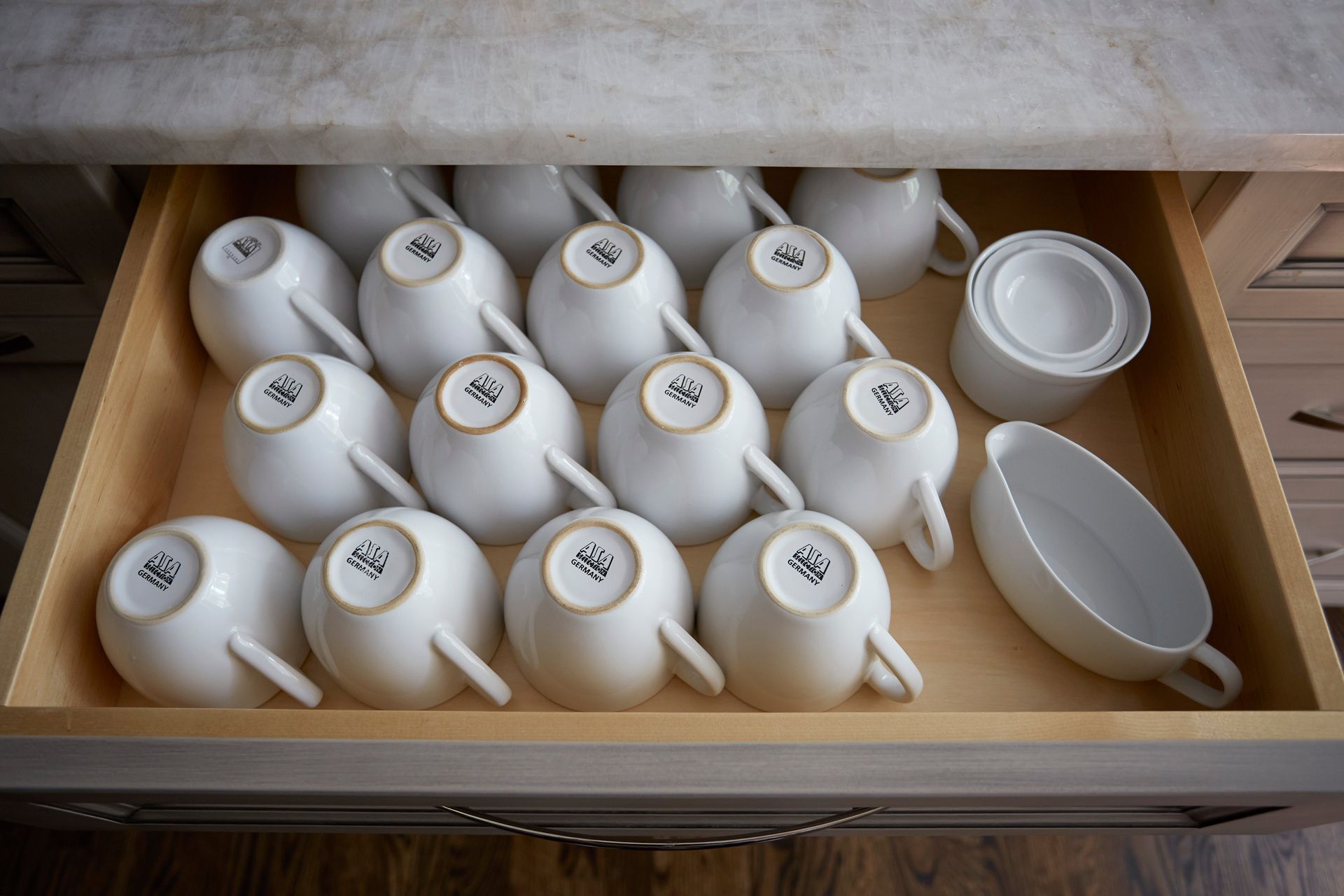 A drawer filled with white coffee cups and saucers.