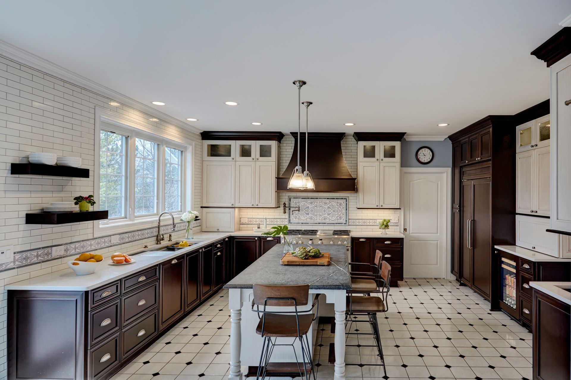 A kitchen with black and white cabinets and a large island in the middle.