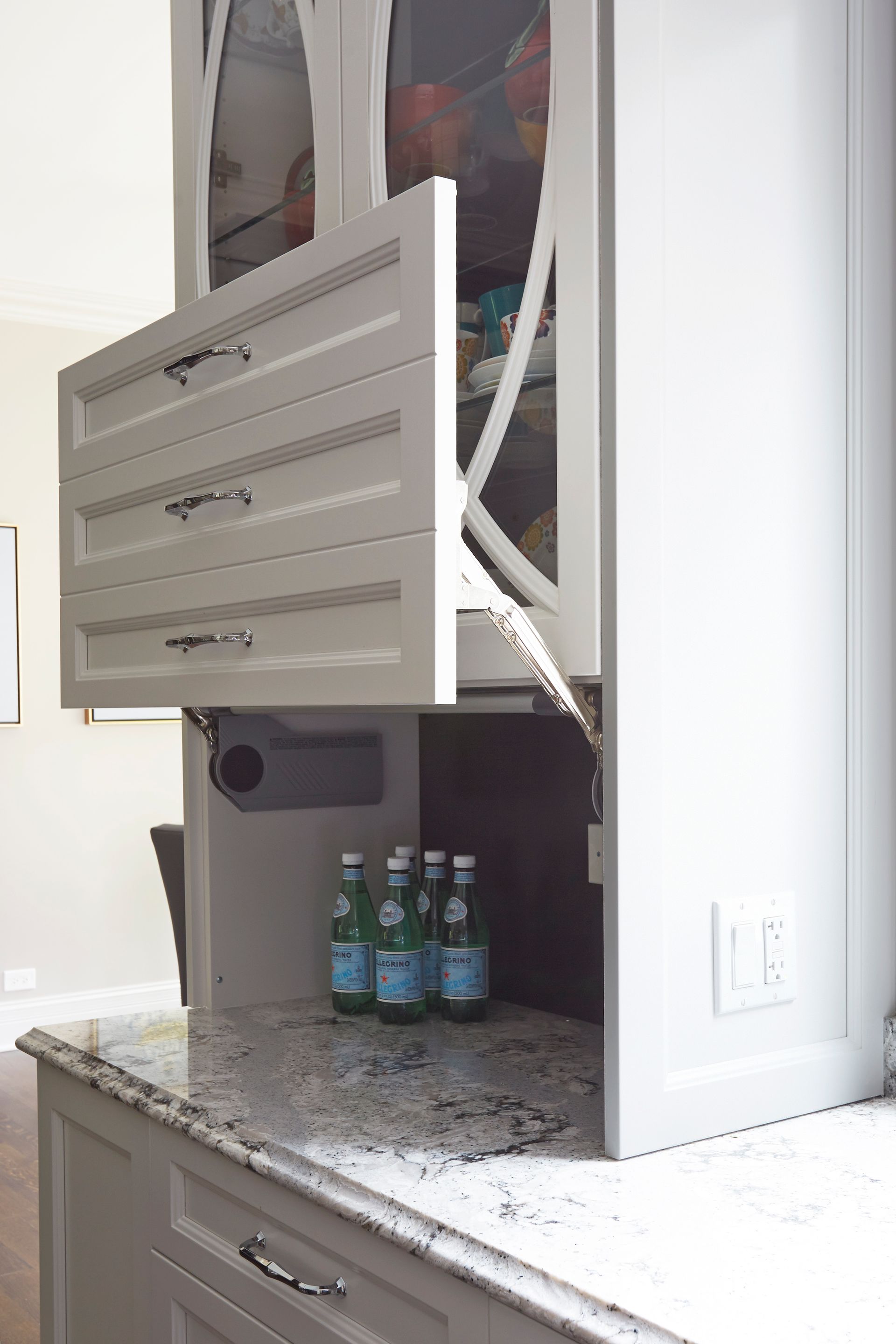 A kitchen with a refrigerator and bottles of water on the counter.