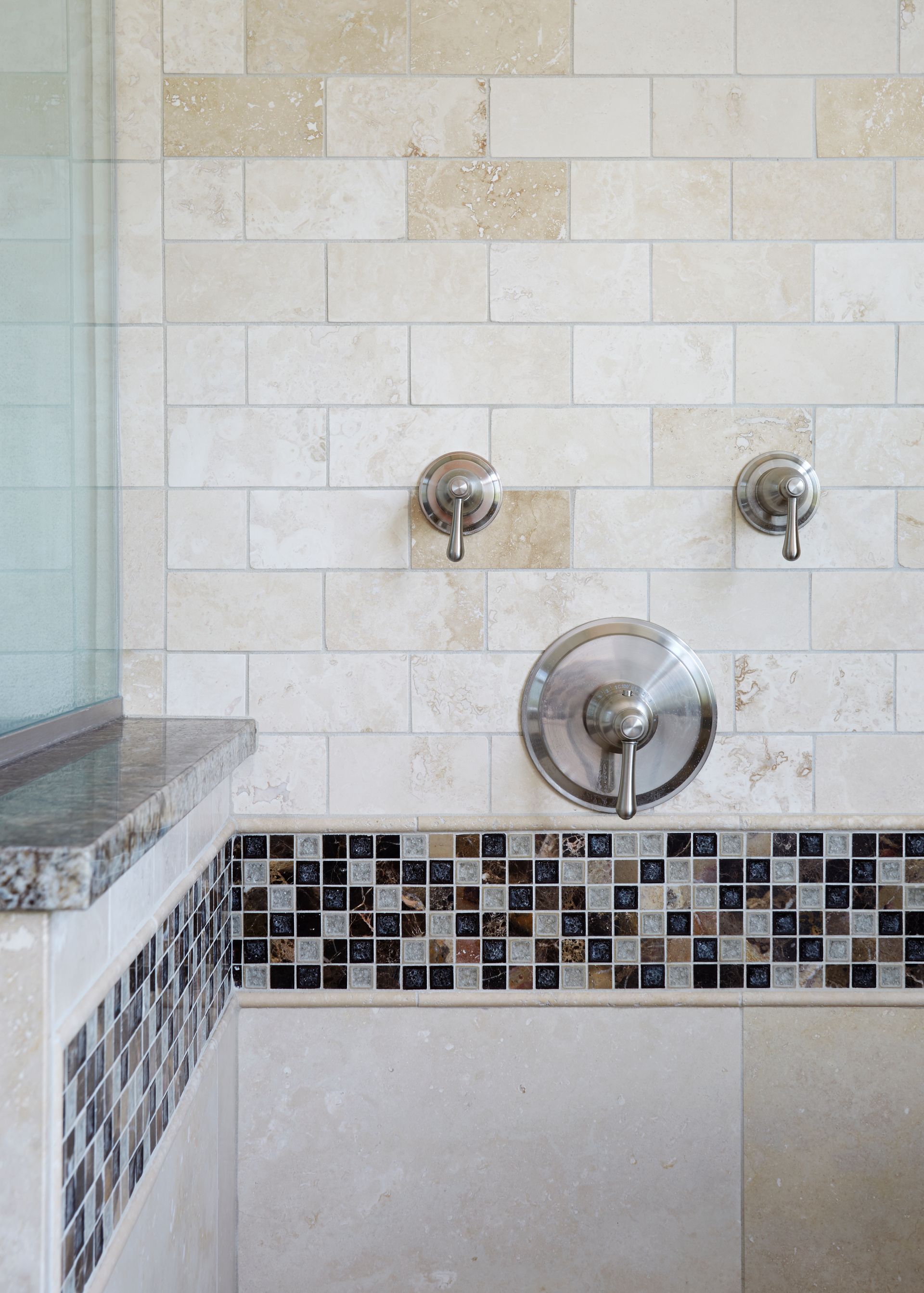 A bathroom with a shower and a mosaic tile border.